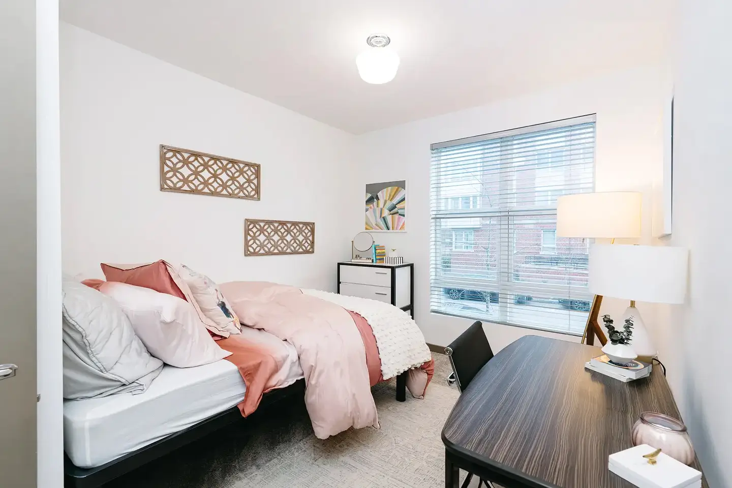 Fully furnished apartment with large window, a study table, a bed, and a dresser.